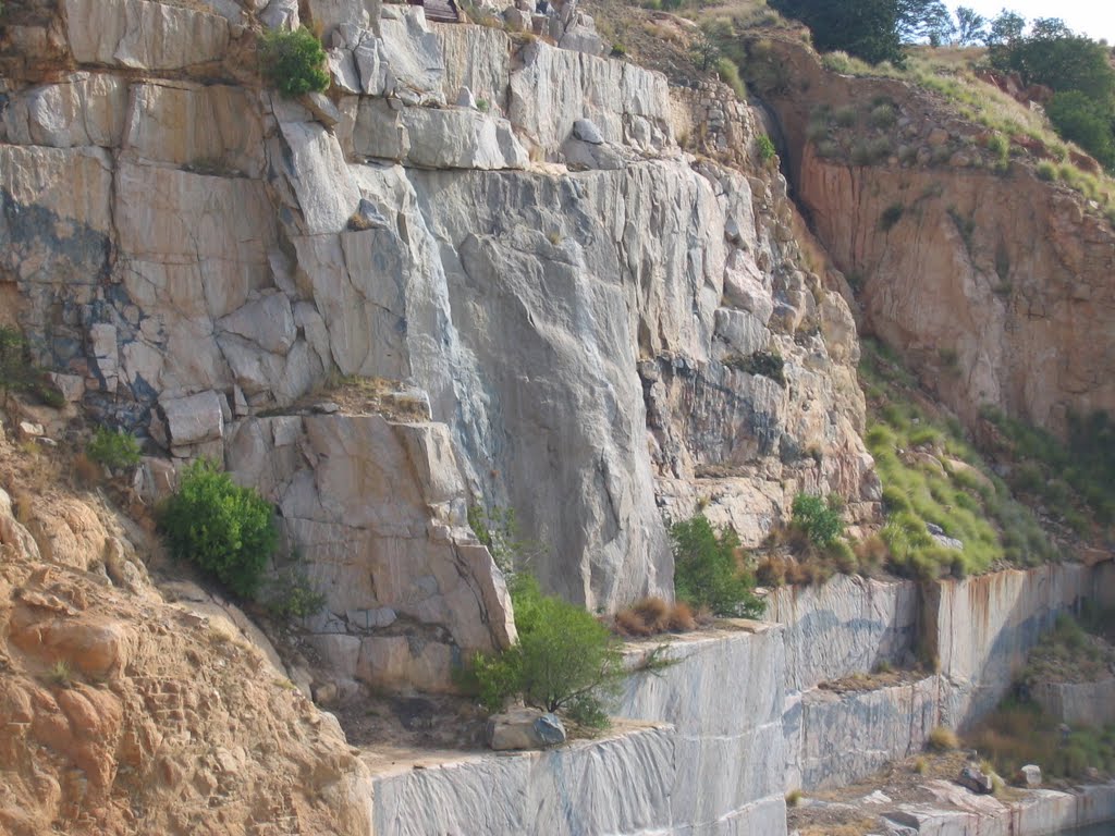 Quarried granite rock face above water filled pit. Note dark grey pseudotachylitic brecchi in granite